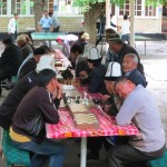Locals in Osh playing chess and ping pong, wearing traditional Kyrgyz hats